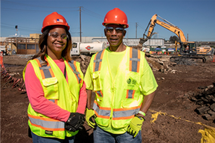 two construction workers standing shoulder to shoulder