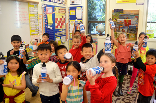 группа школьников, пьющих из своих многоразовых бутылок с водой