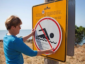mujer publicando un cartel de no nadar
