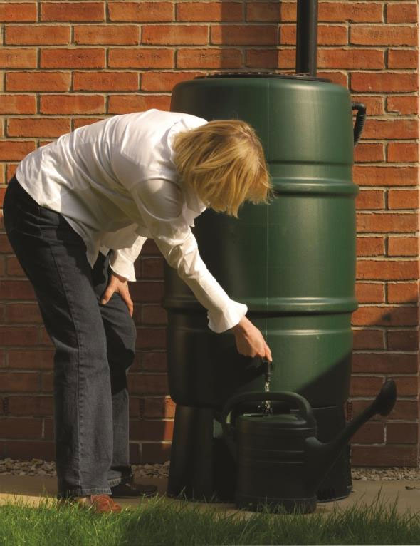 Woman filling a watering can from a rain barrel