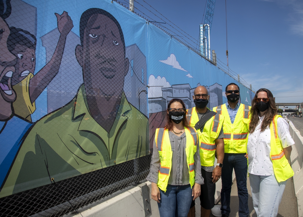 Сотрудники SFPUC стоят перед фреской «История Бэйвью-Хантерс-Пойнт» на Юго-восточной очистной станции.