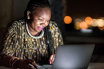 Черная женщина и владелица бизнеса работает за компьютером по ночам.