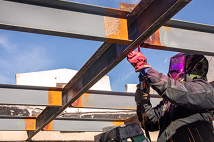 Subcontractor welding steel section of roof