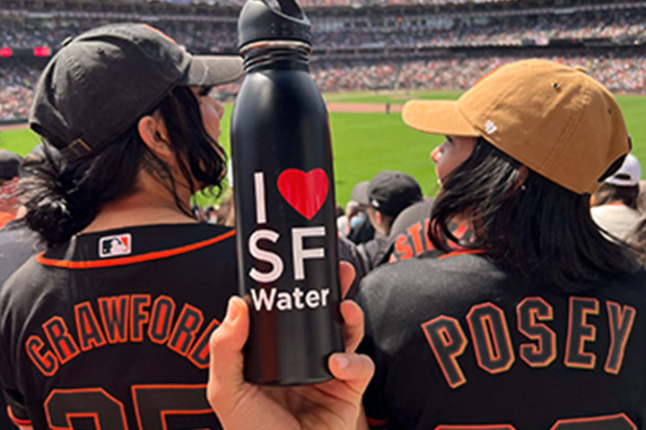 Fans at a Giants game with a water bottle that says, "I love SF Water."