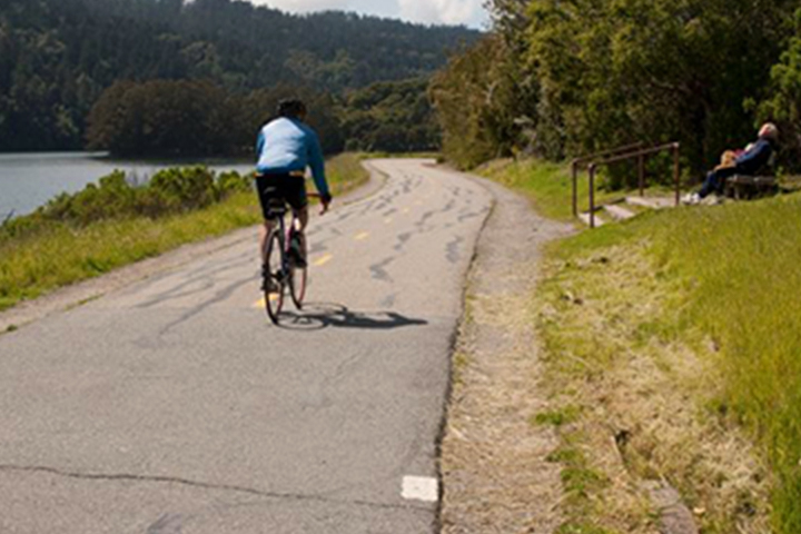 騎自行車者在鋪好的湖邊小道上