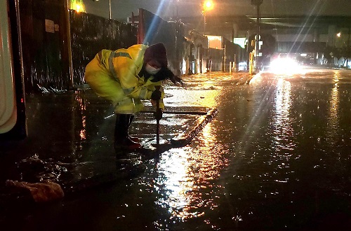Trabajador limpiando una esquina de la calle inundada