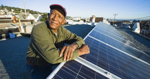 Un hombre se para junto a un panel solar.