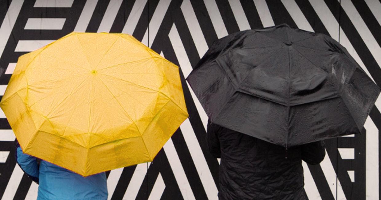 Two umbrellas against a striped wall.