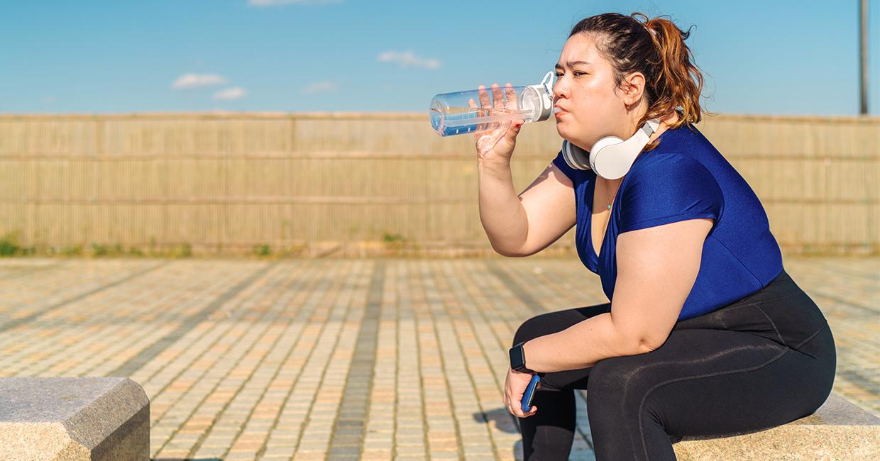 Mujer en ropa de ejercicio bebe de botella de agua reutilizable