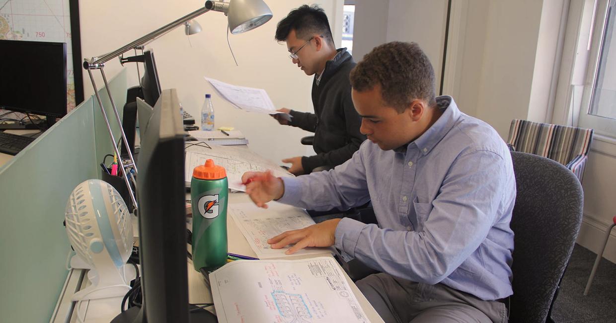 Karl Clayter (al frente) revisando los planes de diseño de ingeniería con su compañero en prácticas Kenneth Mai.