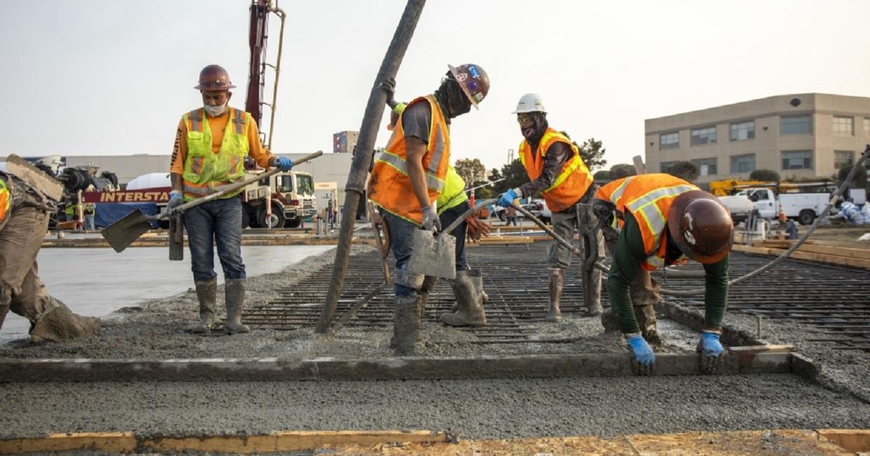 five construction workers pouring concrete