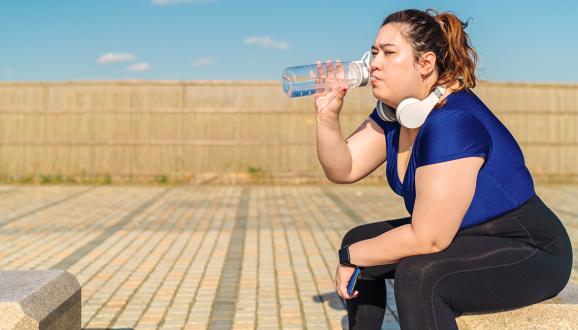 Mujer en ropa de ejercicio bebe de botella de agua reutilizable