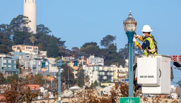 Công nhân SFPUC và cột đèn với nền là San Francisco