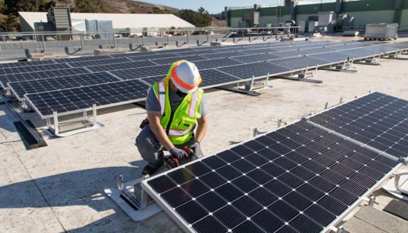 Человек, работающий над панелью солнечных батарей на крыше