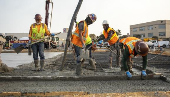 cinco trabajadores de la construcción vertiendo hormigón