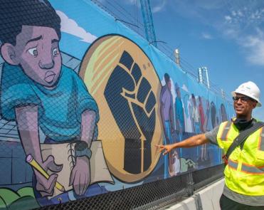 Sirron Norris stands next to a section of his mural